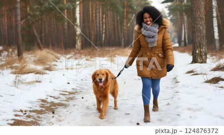 Young African American woman strolling with her best friend - golden retriever dog by winter city park. Amidst a winter wonderland, they explore with joyous hearts. 124876372
