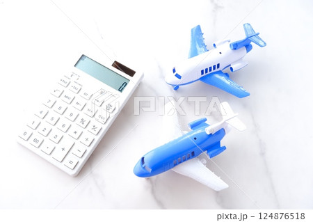 電卓と飛行機で、高騰する航空券代と、高騰する旅行代金のイメージ 124876518