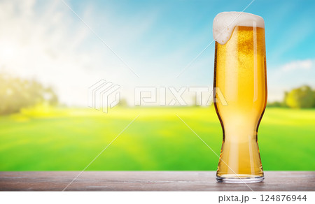 A glass of beer with a golden hue and frothy head 124876944