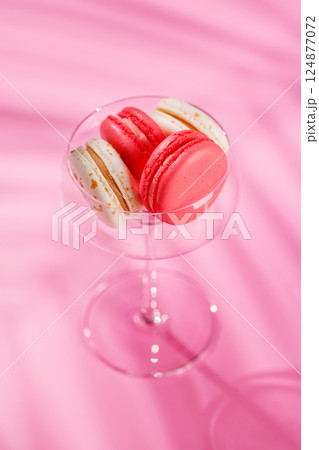 A delightful assortment of colorful macaroons arranged on a vibrant pink background 124877072