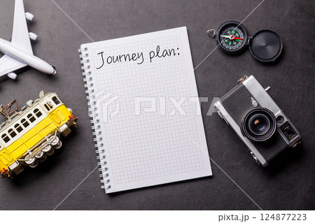 Creative flat lay of a travel-themed desk with notepad for plans 124877223
