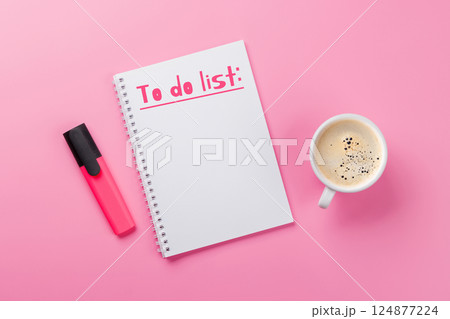 Stylish pink desk with coffee cup, office supplies, and a notepad for writing a to-do list 124877224
