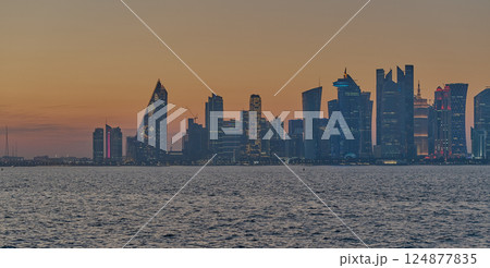 Doha, Qatar-March 21, 2025:  Doha Qatar skyline from the Corniche street at dusk with dhows in the Arabic gulf in the foreground 124877835