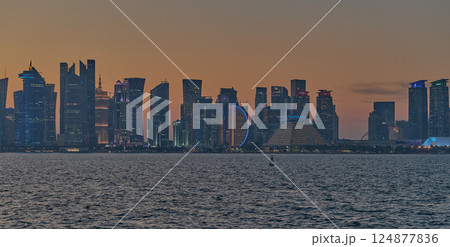Doha, Qatar-March 21, 2025:  Doha Qatar skyline from the Corniche street at dusk with dhows in the Arabic gulf in the foreground 124877836