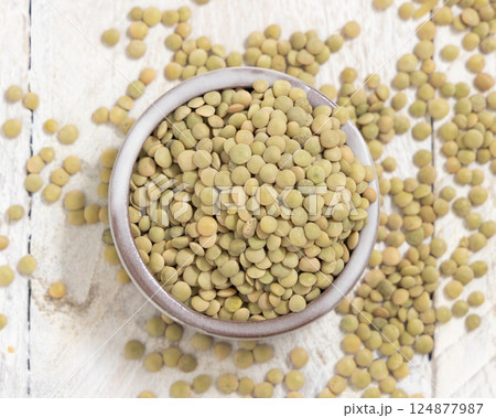Bowl full of dried raw green lentils on white table top view. Traditional mediterranean legume Bowl full of dried raw green lentils on white table top view. Traditional mediterranean legume 124877987