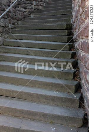 Sturdy stone steps lead upward, surrounded by weathered walls in a historic location during daylight hours 124878528