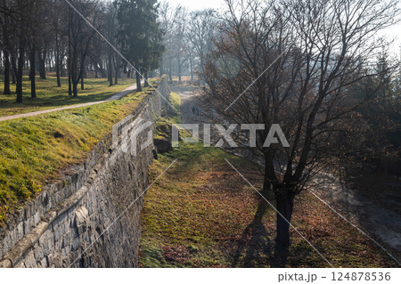 Historic stone wall alongside a winding path through a tranquil park on a foggy morning in autumn Historic stone wall alongside a winding path through a tranquil park on a foggy morning in autumn 124878536