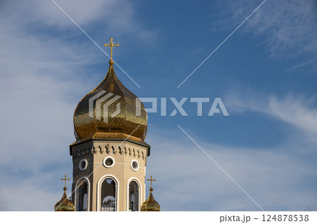 Stunning view of a golden domed church tower against a blue sky showcasing intricate architectural design and peaceful surroundings Stunning view of a golden domed church tower against a blue sky showcasing intricate architectural design and peaceful surroundings 124878538