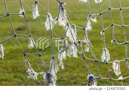 Damaged soccer goal net shows wear and tear after many matches on grassy field Damaged soccer goal net shows wear and tear after many matches on grassy field 124878562