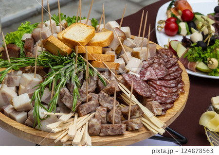 Variety of cured meats and cheeses served on a large platter during a culinary event in an outdoor setting 124878563
