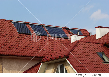 Solar panels installed on red roofs in a sunny residential area during daytime 124878568