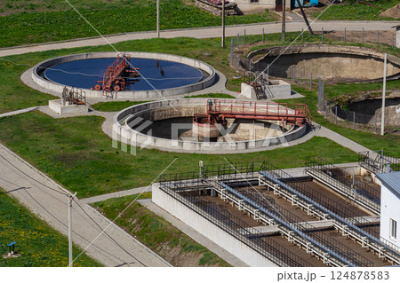 Wastewater treatment facility with circular tanks and processing equipment in a green area Wastewater treatment facility with circular tanks and processing equipment in a green area 124878583