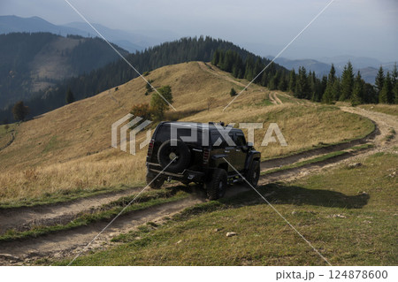 Off-road vehicle navigating a rugged trail in a forested area during daylight hours 124878600