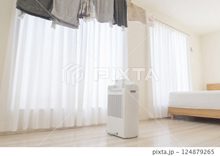 部屋に設置された物干しスタンドと稼働中の除湿機 梅雨時期の部屋干し 部屋に設置された物干しスタンドと稼働中の除湿機 梅雨時期の部屋干し 124879265