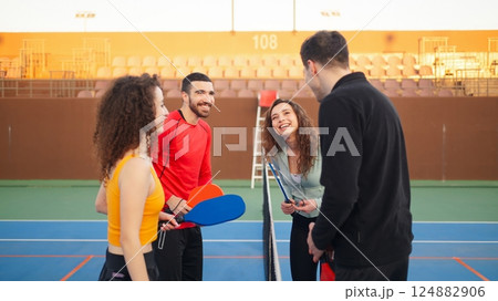 Group of four young adults chatting and smiling after the match on the court stadium Group of four young adults chatting and smiling after the match on the court stadium 124882906