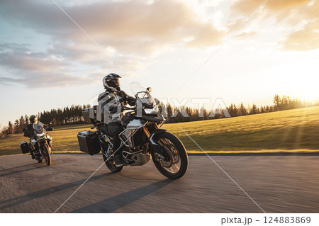 Two Drivers Riding Motorcycle on Empty Road During Sunset. Two Drivers Riding Motorcycle on Empty Road During Sunset. 124883869