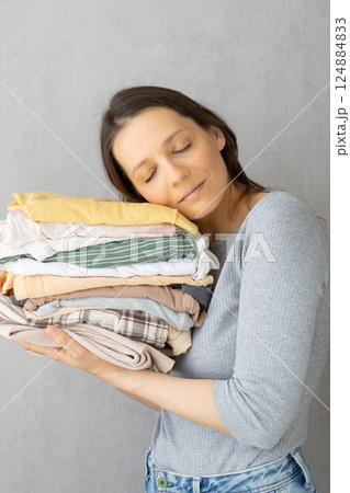Laundry, woman holds stack of clothes in her hands after dry cleaning. housework, cleaning ironing. Laundry, woman holds stack of clothes in her hands after dry cleaning. housework, cleaning ironing. 124884833