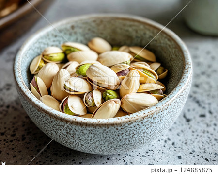 Bowl of pistachios with open shells revealing vibrant green nuts Bowl of pistachios with open shells revealing vibrant green nuts 124885875