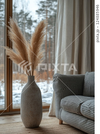 Elegant decorative vase with pampas grass beside a cozy couch in a serene winter setting 124885946