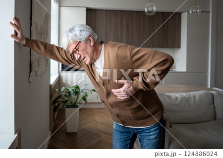 Bending suffering elderly man gasp for breath clutching chest, suspected cardiac episode at home Bending suffering elderly man gasp for breath clutching chest, suspected cardiac episode at home 124886024