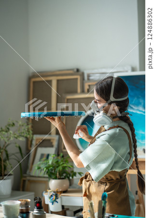 Serious professional female artist examine epoxy resin project on round board post dry in workshop Serious professional female artist examine epoxy resin project on round board post dry in workshop 124886302