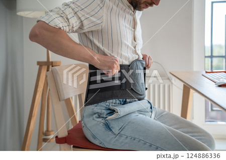 Man wearing back brace at home 124886336