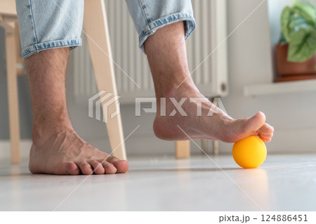 Man massaging arthritic feet with ball at home 124886451
