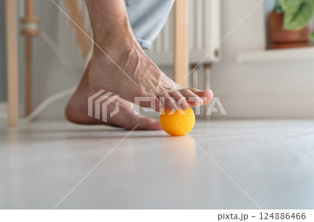 Man massaging arthritic feet with ball at home Man massaging arthritic feet with ball at home 124886466