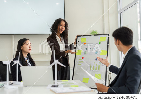 ESG Presentation and Team Collaboration. A professional woman presents ESG metrics to colleagues in a modern meeting room. 124886475