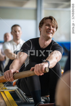 Struggling grimacing sportsmen exert on rowing simulator, paddling refining synchronized movements 124886488