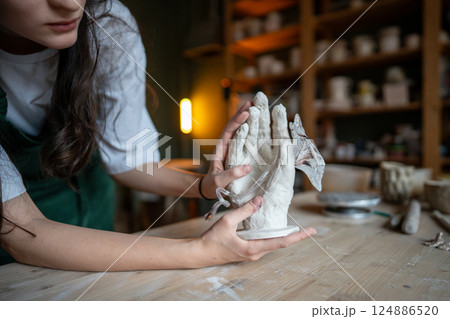 Glassblower forming glass flower in clay hand design for decor production. Contemporary art business 124886520