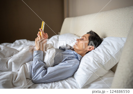 Calm drowsy apathetic woman in bed scrolling smartphone. Social media check, chat in morning relax Calm drowsy apathetic woman in bed scrolling smartphone. Social media check, chat in morning relax 124886550
