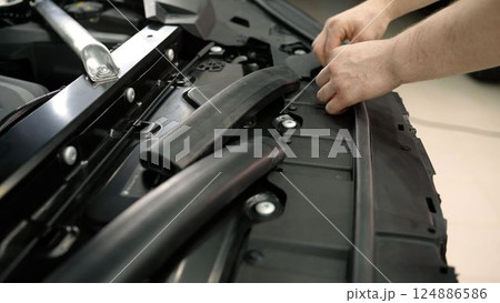 Car underhold repair, close-up. Specialist works on detailing an expensive car. Rubber under the hood, car repair. Car underhold repair, close-up. Specialist works on detailing an expensive car. Rubber under the hood, car repair. 124886586