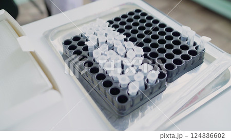 Laboratory Eppendorf tubes inside a metal tray holding test samples for medical research. Eppendorf tubes filled with samples, organized in a tray, await analysis in a medical laboratory, advancing Laboratory Eppendorf tubes inside a metal tray holding test samples for medical research. Eppendorf tubes filled with samples, organized in a tray, await analysis in a medical laboratory, advancing 124886602