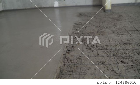 Laying mortar on a concrete floor. Night concrete work on the ground floor leveling the floor Laying mortar on a concrete floor. Night concrete work on the ground floor leveling the floor 124886616
