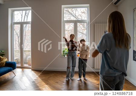 Mother holding smartphone helping kids to record funny dance video for social media 124886718