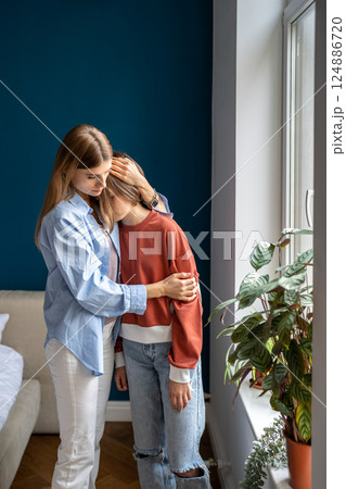 Loving older sister embracing upset crying teen girl, mother hugging supporting teenage daughter Loving older sister embracing upset crying teen girl, mother hugging supporting teenage daughter 124886720