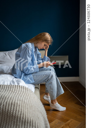 Worried young woman looking at smartphone screen feel nervous about posting on social media 124886730