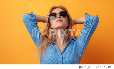 A blonde woman wearing a blue checkered shirt and sunglasses, stretching her arms back 124886946
