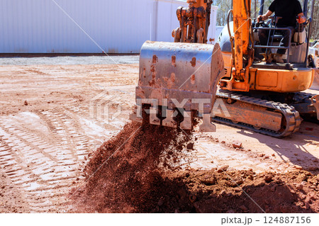 Heavy machinery moves soil at construction site, excavation work under works construction Heavy machinery moves soil at construction site, excavation work under works construction 124887156