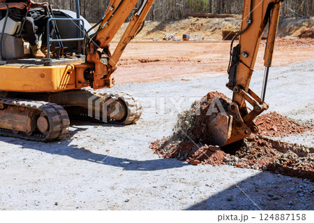 Heavy machinery excavator to digs trench at construction site Heavy machinery excavator to digs trench at construction site 124887158