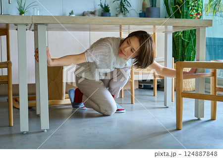 テーブルの下に隠れる女性 124887848