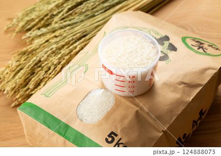 米袋に入ったお米と計量カップ 124888073