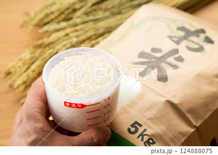 米袋に入ったお米と計量カップを持つ男性の手 124888075