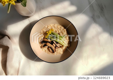 A bowl of oatmeal cooked in chicken broth, topped with fried mushrooms and green onions, arranged in a clean, minimalistic aesthetic 124889023