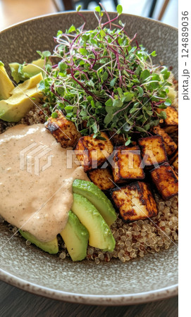 A wholesome bowl of quinoa with grilled tofu, avocado, microgreens, and tahini sauce, perfect for a light, fresh, and nutritious plant-based dish 124889036
