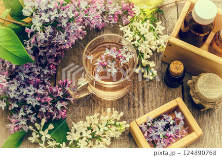 Essential oil and a cup of tea made from lilac flowers 124890768