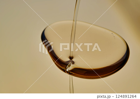 Texture of pouring cosmetic oil on a golden background. Texture of pouring cosmetic oil on a golden background. 124891264