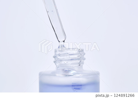 The blue serum drips from the dropper into the bottle. The blue serum drips from the dropper into the bottle. 124891266
