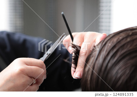 Barbershop. Scissors in hands of hairdresser. Close-up of man's haircut. Hairdresser's master makes haircut with scissors. Barbershop. Scissors in hands of hairdresser. Close-up of man's haircut. Hairdresser's master makes haircut with scissors. 124891335